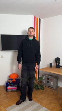 Svart hoodie med framficka och präglad logotyp, kombinerad med mörka jeans med intrikat broderi. Skorna är blanka och bruna.