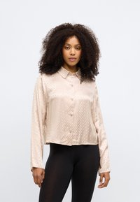 Ροζ, σατέν πουκάμισο με κουμπιά και διαμαντένιο μοτίβο, με μακριά μανίκια και κλασικό γιακά, συνδυασμένο με μαύρες κολάν.