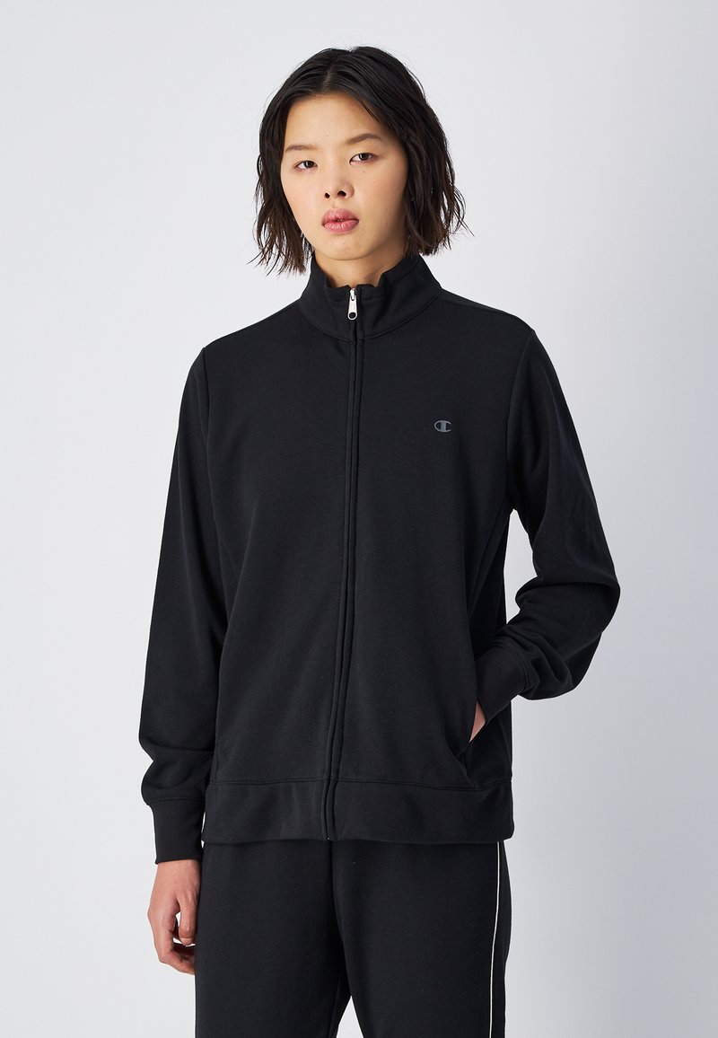 Czarna kurtka na zamek, wykonana z miękkiego materiału, z wysokim kołnierzem, z logo na klatce piersiowej i bocznymi kieszeniami. Klasyczny, sportowy krój.