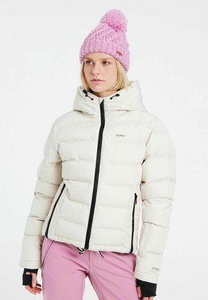 White puffer jacket with a fitted hood, black zipper, and side pockets. Paired with a pink knit hat featuring a pom-pom on top.