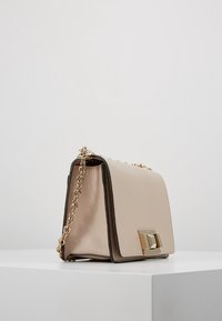 Borsa a spalla in pelle beige con tracolla in catena dorata, forma rettangolare, texture liscia, dotata di una chiusura metallica e bordi a contrasto.