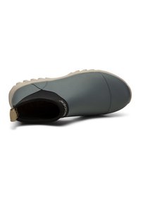 Chaussure en caoutchouc grise à enfiler avec une semelle beige et un col élastique noir marqué « Woden », vue de dessus.