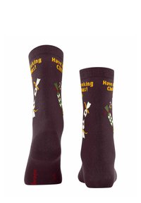 Dunkelbraune Socken mit festlichen Grafiken, darunter ein Vogel und der Text "Frohe, quakende Weihnachten!" in Gelb. Gehäkelte Textur, bis zur Wade.