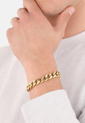 Bracciale in oro e argento alla rovescia, caratterizzato da maglie spesse con colori alternati e una texture liscia. Indossato su un maglione chiaro.