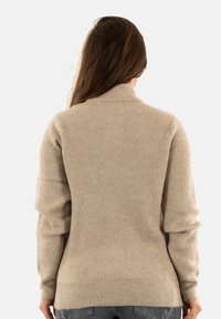 Maglione beige a coste con colletto alto e maniche lunghe, caratterizzato da una forma aderente e un tessuto strutturato, con dettagli delle cuciture visibili sul retro.