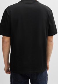 Zwarte katoenen t-shirt met ronde hals, korte mouwen en een eenvoudige rechte zoom, zonder opvallende patronen of accenten.