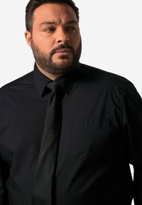 Černá košile na knoflíky s klasickým límcem, s náprsní kapsou a hladkou texturou, doplněná o odpovídající černou kravatu.