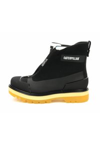 Botte cheville noire avec fermeture éclair, tige en tissu texturé, et semelle en caoutchouc jaune contrastante avec un motif de bande de roulement robuste.