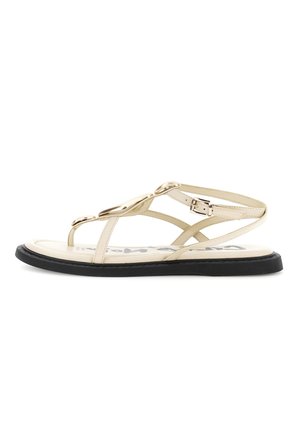 Sandalo piatto beige con suola nera, punta aperta, sottili cinturini, decorazioni ovali dorate e fibbia regolabile alla caviglia.