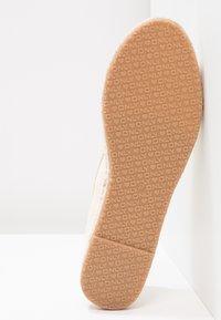Semelle d'une chaussure marron clair avec les motifs "ONLY" et des cœurs embossés, indiquant la taille 37, inclinée contre un fond blanc en angle.