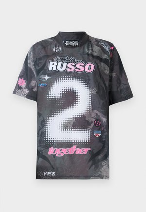 Kratkoročni dres v črni barvi z grafičnimi vzorci, ki prikazuje "2" v belih pikah, rožnate poudarke ter več logotipov v različnih barvah.