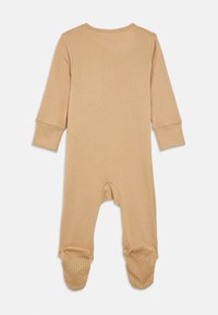 Mameluco para bebé beige de mangas longas com parte inferior com pés e pontos antiderrapantes nas solas, mostrado de costas sobre um fundo branco.