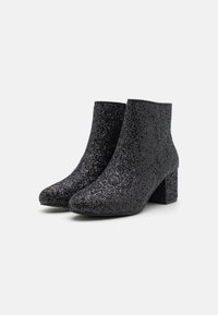Botine negre cu glitter, cu vârf ascuțit, superior texturat și toc bloc. Suprafața are un finisaj strălucitor și o talpă netedă.