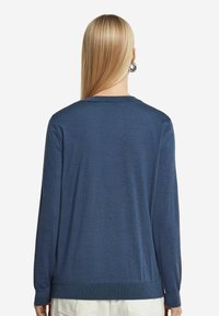 Granatowy sweter z długim rękawem wykonany z miękkiego materiału, z okrągłym dekoltem i prążkowanym wykończeniem u dołu i przy mankietach, gładka tekstura, bez widocznych wzorów.