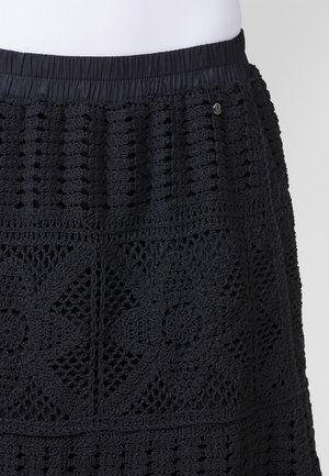 Jupe noire en crochet avec un design texturé et des motifs floraux, taille élastique et petits détails en métal.