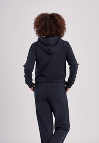 Mörkblå hoodie med dragsko i huvan, tillverkad av mjukt tyg. Har ribbade ärmslut och midja, i kombination med matchande sweatpants.