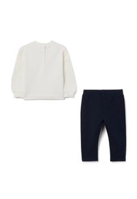 Pull-over long beige à manches longues avec fermeture à boutons et pantalon en jersey bleu marine, tous deux en tissu de coton doux.