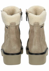 Botas de tobillo de ante en beige claro con un puño de piel de oveja blanca y suave. Cremalleras laterales y una suela gruesa en beige claro. Textura suave en todo el calzado.