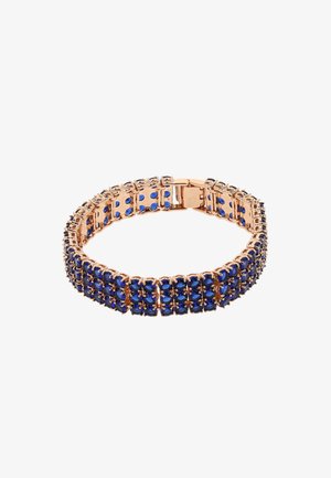 Bracciale dorato con gemme blu incastonate in un design flessibile e con un clasp sicuro. Le pietre sono tagliate a forma ovale e disposte in file.