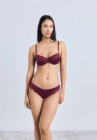 Viininpunainen pitsirintaliivit ja niihin sopivat pikkuhousut, joissa on kukkakoristeet, säädettävät hihnat ja sileä viimeistely. Setti esittelee tyylikkään muotoilun.