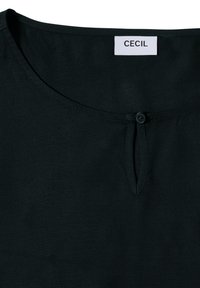 Zwarte blouse van CECIL met een ronde halslijn, kleine knoopsluiting en zachte textuur. Eenvoudig ontwerp zonder patronen of extra accenten.