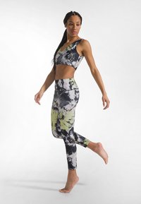 Sport-bh och leggingsset i mönster med tie-dye. Materialen består av blandningar av svart, grått och limegrönt. Figursydd design, mjuk textur.