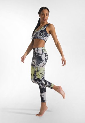 Sports-bh og leggings sæt med tie-dye mønster. Materialerne har blandinger af sort, grå og limegrøn. Tætsiddende design, glat tekstur.