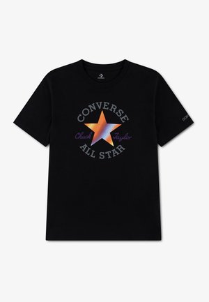 Schwarzes T-Shirt mit kurzen Ärmeln und einem großen orange-blauen Farbverlauf-Stern in der Mitte, umgeben von dem Text "Converse All Star Chuck Taylor."