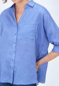 Camicia azzurro chiaro con colletto, taschino singolo sul petto e vestibilità leggermente comoda. Realizzata in un tessuto leggero e testurizzato.
