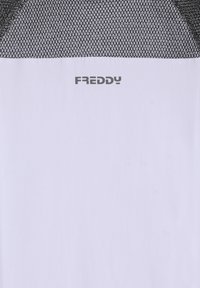 Camiseta deportiva blanca con sección superior de malla negra, con el logo "FREDDY" en gris. Textura suave con diseño transpirable.