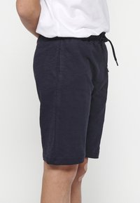 Marineblaue Shorts aus einem weichen, strukturierten Stoff, mit einem elastischen Bund und Kordelzug sowie Seitentaschen.
