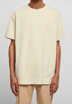 Beige Baumwoll-T-Shirt mit lässiger Passform, rundem Ausschnitt und kurzen Ärmeln. Glatte Textur und minimalistisches Design ohne sichtbare Muster.
