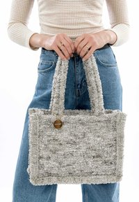 Borsa a tracolla grigia con tessuto morbido, manici corti e un'etichetta decorativa. Design rettangolare semplice con minimi dettagli.