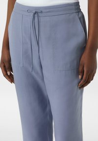 Hellblaue, lässig geschnittene Hose mit elastischem Bund, verstellbarem Kordelzug und zwei vorderen Taschen. Glatte Stoffoberfläche.