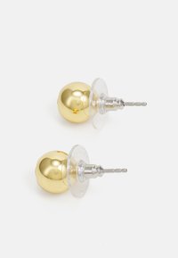 Orecchini in metallo color oro con un design sferico liscio. Fondi in plastica trasparente e perni in metallo argentato. Due orecchini esposti.