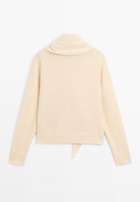 Kremowy, dzianinowy sweter z golfem, długimi rękawami i krótkim obszyciem z tylnym wiązaniem. Miękka faktura, minimalistyczny design.