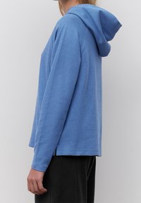 Hoodie i ljusblått stickat tyg, med långa ärmar och en avslappnad passform med rak nederkant. Subtil textur genom hela plagget.