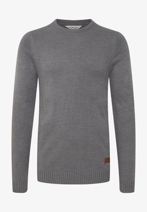 Szary sweter o prążkowanej strukturze, okrągłym dekolcie i długich rękawach. Posiada brązową skórzaną naszywkę z logotypem na dolnej części.