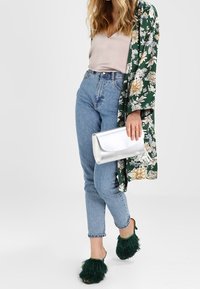 Blomstret grøn kimono, beige top, blå højtaljede jeans, sølv clutch og fuzzy grønne hæle. Detaljerede teksturer og livlige farver.