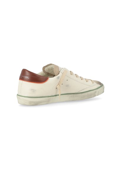 Sneaker in tela con upper color crema, linguetta in pelle marrone, lacci beige, suola in gomma verde e lievi segni di usura per un aspetto vissuto.