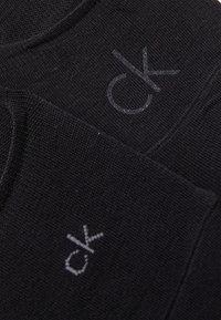 Crni pamuk s diskretnim, utisnutim "ck" logotipom u sivoj boji. Tekstura je mekana, s čistim, minimalističkim dizajnom.
