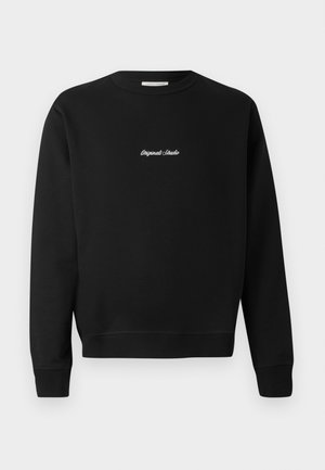Sweatshirt noir avec un col rond, des manches longues et des poignets côtelés, avec "Original Studio" brodé en blanc sur le devant.