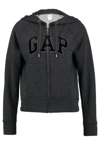 Sweat à capuche zippé gris en tissu doux, avec une poche kangourou, une capuche à cordon de serrage et un grand lettrage noir "GAP" à l'avant.