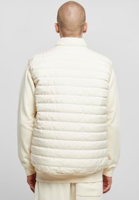 Kerge, kreemikasvärviline sulejope vest horisontaalsete õmblustega, kõrge krae ja soonikkoes äärega. Pehme tekstuur, minimalistlik disain.