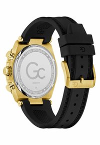 Black rubber strap watch with a gold stainless steel case, large round face, and chronograph functions. Features a sapphire crystal back.