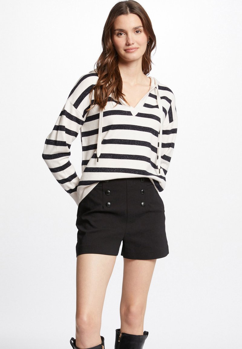 Gestreepte pullover in crème en marineblauw met trekkoorden en een V-hals, gecombineerd met hoge zwarte shorts met dubbele knoopdetail.