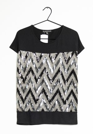 T-shirt nera con maniche corte, caratterizzata da un motivo a chevron in paillettes argento e nero, con una fascia inferiore nera uniforme.
