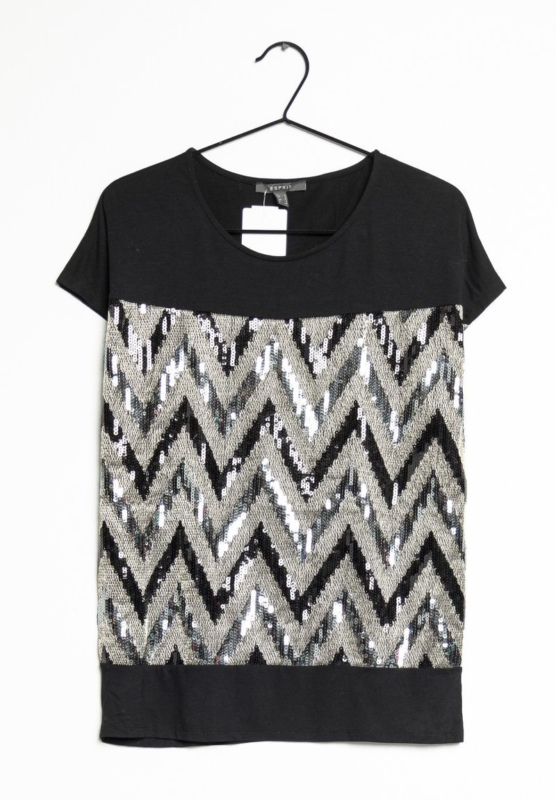 Černé tričko s krátkým rukávem, které má flitrový chevronový vzor v černé a stříbrné barvě, s pevným černým spodním lemem.