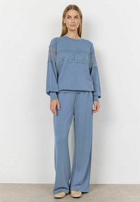 Light blue loungewear set featuring a long-sleeve top with lace detailing and loose-fitting pants. Soft, comfortable fabric with a relaxed silhouette.