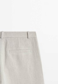 Pantalon en lin beige clair avec poche arrière passepoilée et passants pour ceinture, présenté sur un fond blanc.